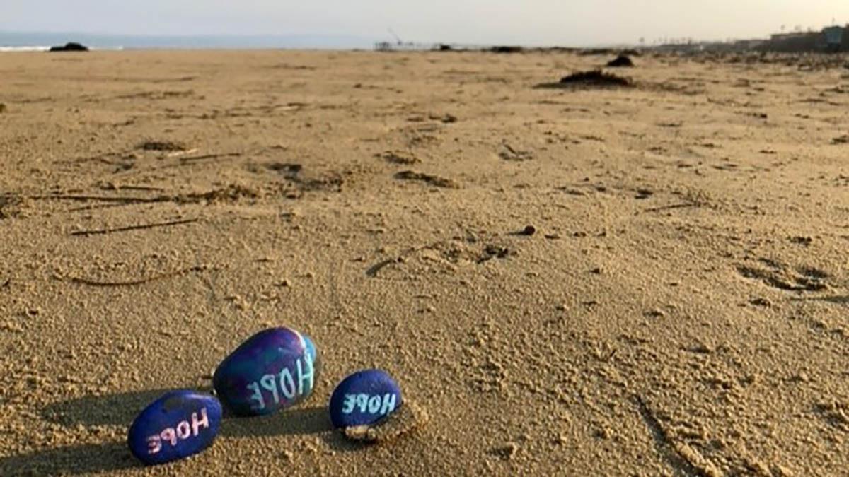 Photo of three rocks on the beach with ocean in background.