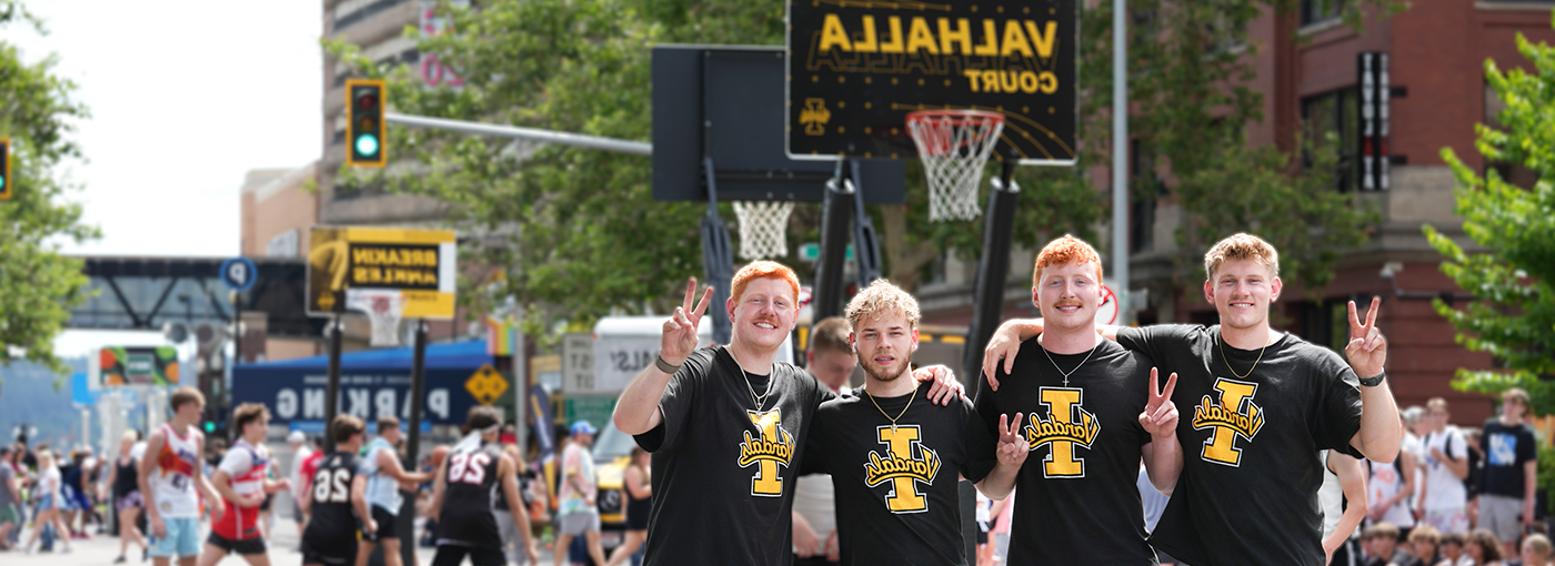 Four basketball players in black shirts in front of Vandal hoop.