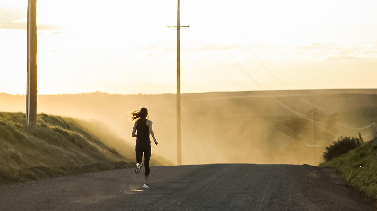 Photo of woman running down a dirt road.