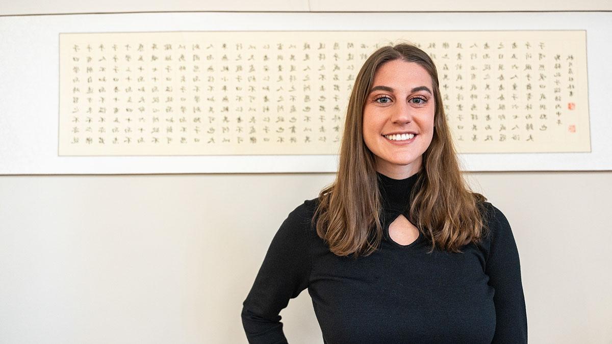 Woman stands in front of art with Japanese characters.